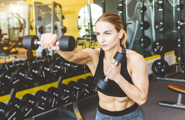 Working out with dumbbell weights at the gym.Fitness Women exercising are lifting dumbbells. Fitness muscular body.Workout at gym. - Foto, imagen