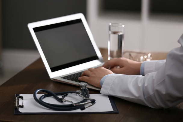 Professional doctor working on laptop in office, closeup - Foto, imagen