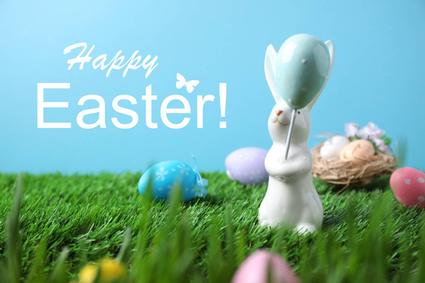 Easter bunny figure and painted eggs on green grass - Foto, Imagen
