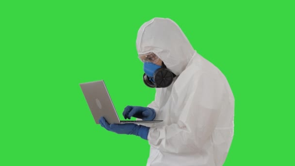 Arzt im Schutzanzug arbeitet am Laptop und hat gute Ergebnisse auf einem Green Screen, Chroma Key. - Filmmaterial, Video