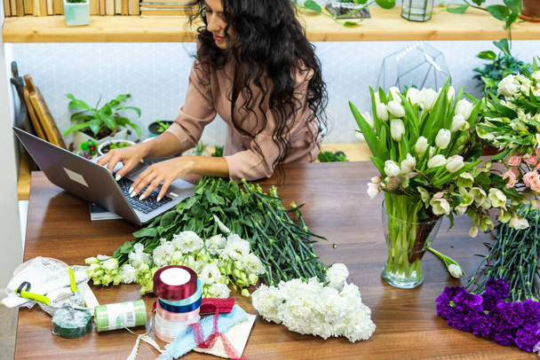 Attractive young woman florist is working in a flower shop. - 写真・画像