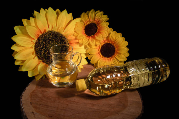 slunečnice olej dřevo sklo láhev černé pozadí žluté - Fotografie, Obrázek
