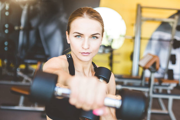 Working out with dumbbell weights at the gym.Fitness Women exercising are lifting dumbbells. Fitness muscular body.Workout at gym. - Fotoğraf, Görsel