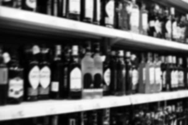 店内の棚の上のさまざまな種類のアルコール、ディスプレイ上のたくさんの風味豊かなウォッカガラスボトル、黒と白のショットの食料品店アルコール飲料のコンセプトを販売しています - 写真・画像