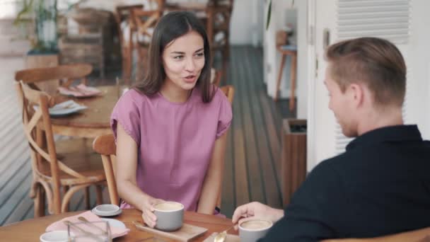 Junges Paar trinkt Kaffee im Café, Mann und Mädchen reden und lachen - Filmmaterial, Video