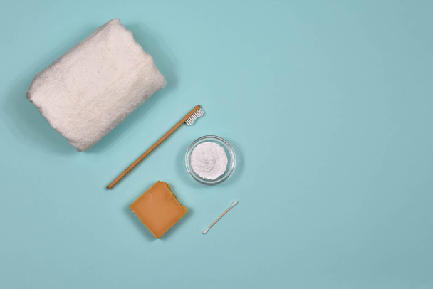 Null-Abfall-Konzept. Zahnbürste, Zahnpuder, Handtuch und Seife auf blauem Hintergrund. Umweltfreundliche Bambuszahnbürste. Blick von oben. - Foto, Bild
