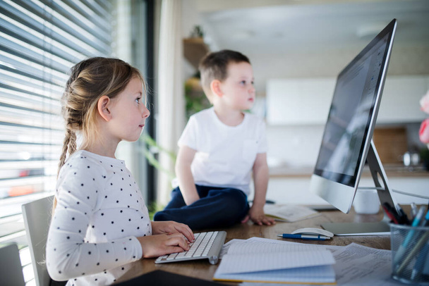 Kleine Mädchen und Jungen nutzen den Computer zu Hause. Coronavirus und Quarantäne-Konzept. - Foto, Bild
