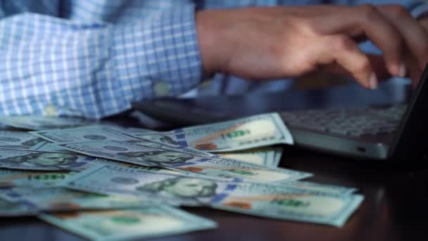 Hundred dollar bills falling on table of freelancer working on laptop - Πλάνα, βίντεο