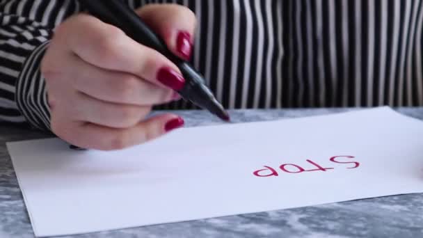 Keskellä on arkki, jossa naiskäsi kirjoittaa stop coronavirus punaisella merkkiaineella valkoisella paperilla osoittaa sen lähikuva kamerassa. Käsite karanteeni koronavirus maailmassa
. - Materiaali, video