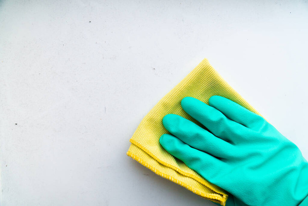 ręka w zielonej gumowej rękawicy wyciera stół z żółtym włóknem szmaty, koncepcja czystości w domu, sprzątanie w domu - Zdjęcie, obraz