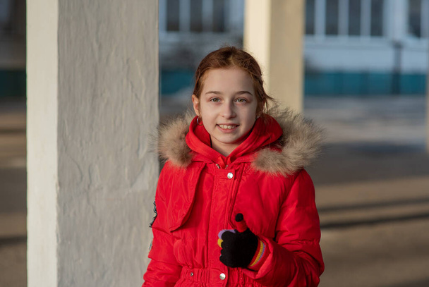 Κοντινό πορτραίτο ενός όμορφου εννιάχρονου κοριτσιού. Μαθητής με χειμωνιάτικα ρούχα. Κορίτσι 9 χρονών. Έφηβος, πορτρέτο. Κορίτσι με κόκκινο μπουφάν. Νέα γενιά. τα παιδιά της γενιάς Z - Φωτογραφία, εικόνα
