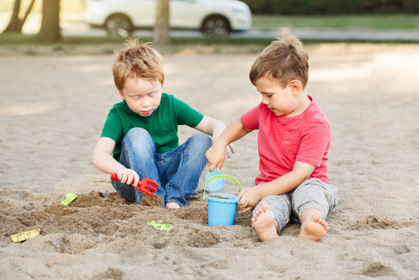 Dwoje białych dzieci bawiących się zabawkami na plaży. Mali chłopcy bawią się razem na placu zabaw. Letnia aktywność na świeżym powietrzu dla dzieci. Czas wolny styl życia dzieciństwo. - Zdjęcie, obraz