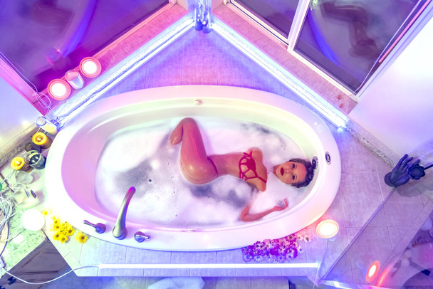 A gorgeous brunette hispanic woman takes a luxurious bath at home - Foto, afbeelding