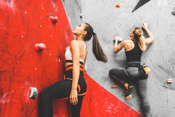 Athletes climber moving up on steep rock, climbing on artificial wall indoors. Extreme sports and bouldering concept - Foto, Imagen