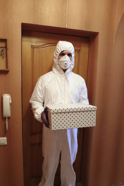 home delivery, a man in a protective suit, mask and gloves brought a box to the flu epidemic, coronavirus pandemic - Foto, immagini