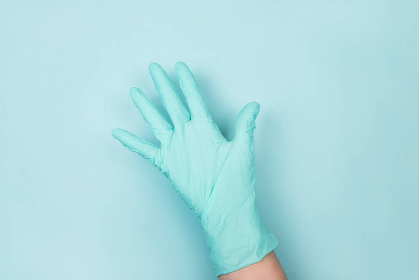 Vrouw hand in medische handschoenen geïsoleerd op blauwe achtergrond. - Foto, afbeelding