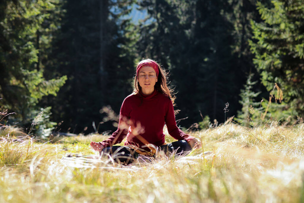 Chica joven medita en el bosque en posición de loto. Concepto - unidad con la naturaleza y armonía interior
 - Foto, Imagen