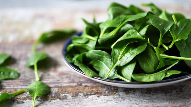 Fresh baby spinach on a plate. Juicy spinach leaves. Diet concept. Vegan food. - Фото, зображення