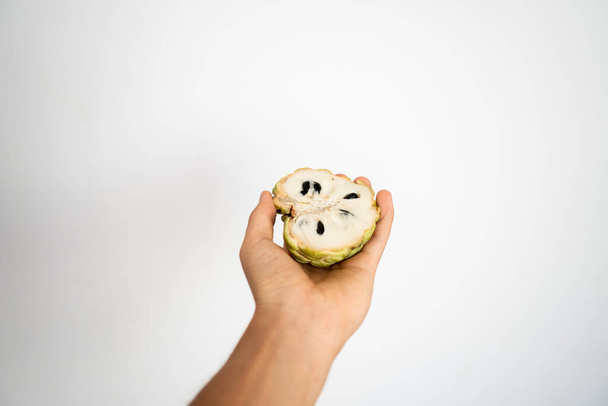 Female hand holding a three ripe sweetsop custard apple on a white background. - Фото, зображення