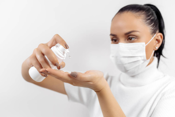 Woman in protective mask use hand sanitizer. Coronavirus protection. - Foto, afbeelding