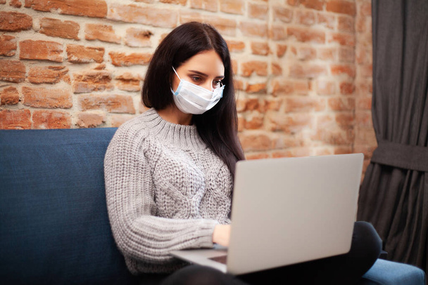Γυναίκα μείνετε στο σπίτι κατά τη διάρκεια μιας επιδημίας και εργάζονται σε ένα φορητό υπολογιστή - Φωτογραφία, εικόνα