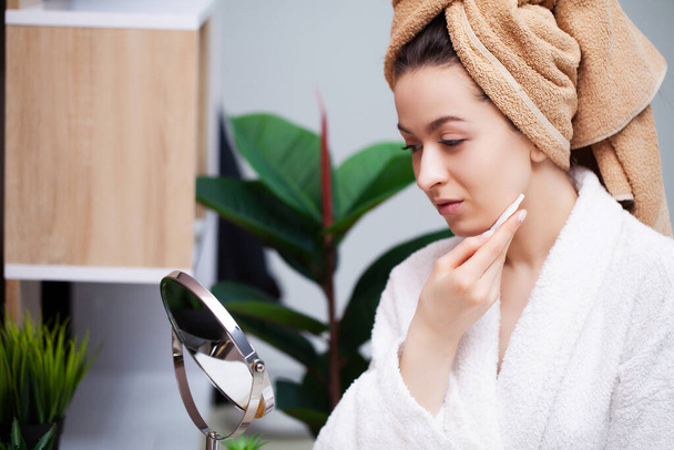 Femme mignonne dans la salle de bain faisant procédure cosmétique pour les soins de la peau du visage
 - Photo, image
