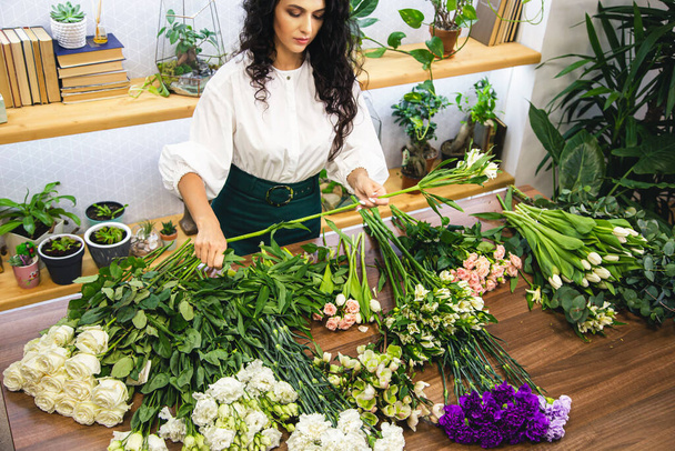 Attractive young woman florist is working in a flower shop. - Photo, Image