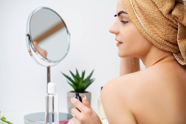 可愛いです女性でバスルームで顔のスキンケアのための化粧品手順を行う - 写真・画像