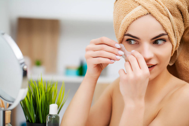 Linda mujer en el baño utilizar parches para el cuidado de la piel facial
 - Foto, imagen
