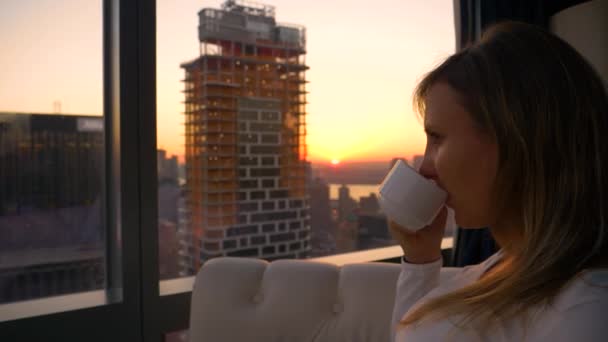 FERMER : Femme prend une gorgée de café tout en regardant le lever du soleil de la chambre d'hôtel - Séquence, vidéo
