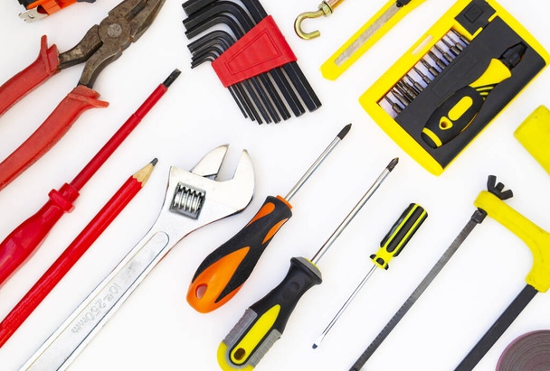 Construction tools lie on a white background. Screwdrivers, a saw, a gas wrench, a pencil, pliers, a screwdriver lie as a pattern. The concept of construction, home repair. - Photo, image