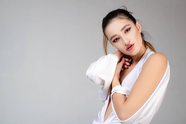 Beautiful young woman, fashion and the image of the luxury make-up. Fashion photo of a beautiful young woman in a pretty dress over gray background. Fashion photo. - 写真・画像