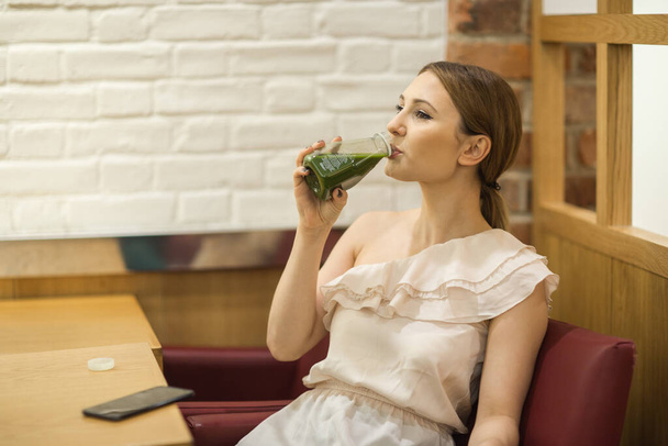 jonge vrouw zitten in een coffeeshop genieten van een sap - Foto, afbeelding
