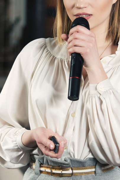 Obchodní a řečové téma: žena v bílé blůze s černým mikrofonem, uvnitř - Fotografie, Obrázek