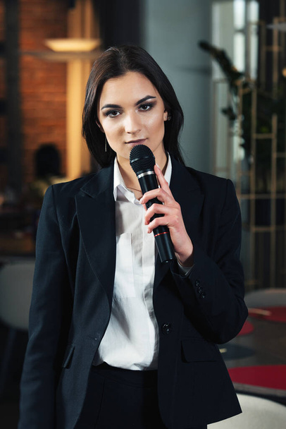 Biznes i temat mowy: kobieta w białej koszuli z czarnym mikrofonem, wewnątrz - Zdjęcie, obraz
