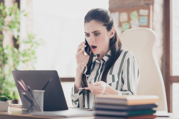Close-up portrait of nice attractive worried mad angry outraged girl partner company founder talking on phone discussing failure at modern brick loft industrial interior style workplace workstation - Foto, imagen