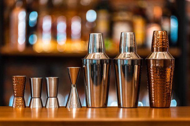 золотой и серебряный коктейль шейкер на фоне стойки бара
 - Фото, изображение