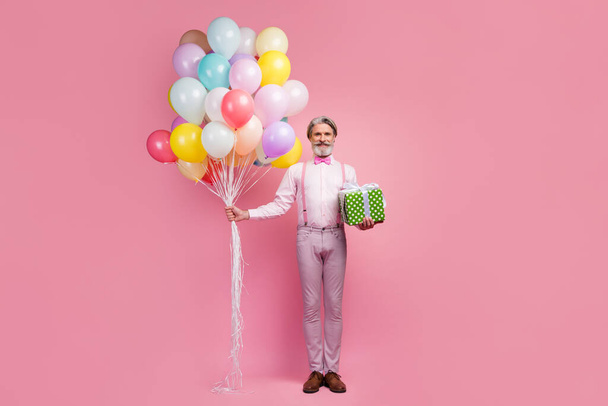 Full length body size view of his he nice attractive imposing elegant fashionable cheerful grey-haired man holding in hands bunch air balls giftbox isolated over pink pastel color background - Φωτογραφία, εικόνα