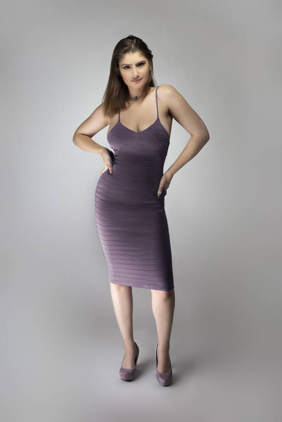 Female fashion model wearing a trendy slim fit purple, or lavender violet summer dress in a studio for summer and spring collection catalog. She is sexy and looking confident - Фото, изображение