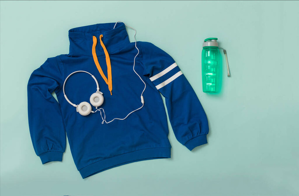 Sportovní bunda, sluchátka a tekuté láhve na modrém pozadí. - Fotografie, Obrázek