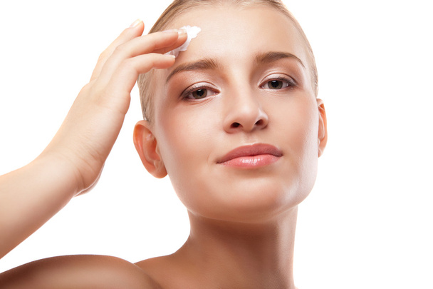 Woman applying moisturizer cream on face isolated - Фото, изображение
