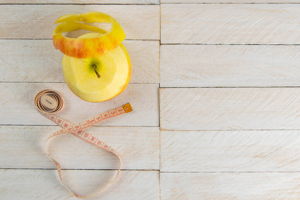 Healthy lifestyle concept. Yellow apple and centimeter on white wooden table close-up and copy space. Fruit Diet Concept. - Foto, Imagen