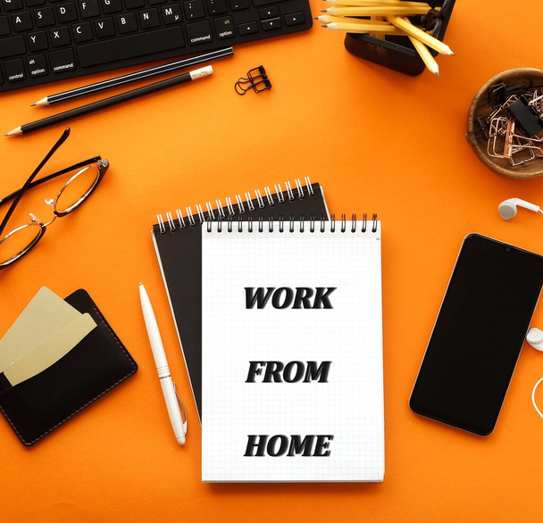 Stay home, work from home message. Coronavirus Covid -19 quarantine concept.  Office desk top view  on orange background.Copy space. - Foto, afbeelding