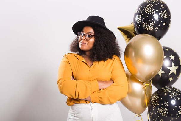 Holidays, birthday party and fun concept - Portrait of smiling young African-American young woman looking stylish on white background holding balloons. - Foto, Bild