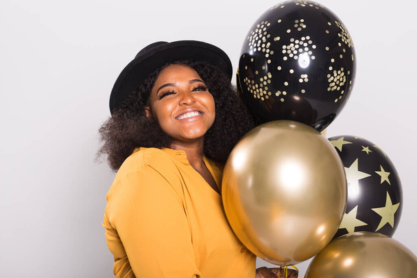 Vacanze, festa di compleanno e concetto di divertimento Ritratto di giovane donna afro-americana sorridente alla moda su sfondo bianco che tiene palloncini
. - Foto, immagini
