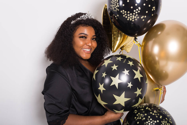 Відпустка, вечірка на честь дня народження і веселий концепт - Портрет усмішки молодої афро-американської дівчини, яка виглядає стильно на білому фоні, тримаючи повітряні кулі. - Фото, зображення