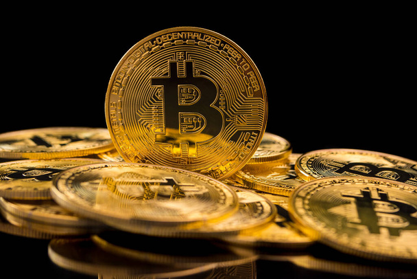 Moedas de ouro com símbolo bitcoin em um fundo preto
. - Foto, Imagem