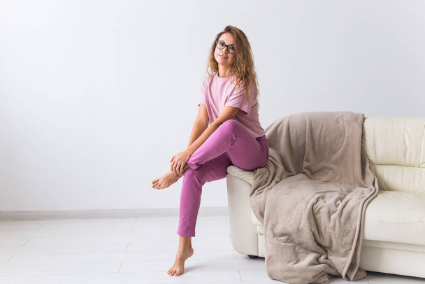 Junge attraktive Frau in schönem, buntem Pyjama posiert als Model in ihrem Wohnzimmer. Bequeme Nachtwäsche, Entspannung zu Hause und weibliches Modekonzept. - Foto, Bild