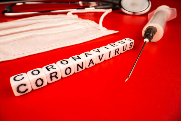 Pandemie- und Viruskonzept - Coronavirus-Text mit Spritze und Phonendoskop auf rotem Hintergrund. Neuartiges Coronavirus Covid-19. - Foto, Bild