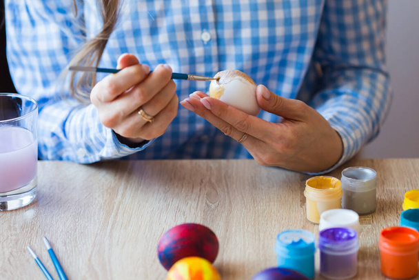 Holidays, handmade and creation concept - Happy young woman draws on Easter egg, close-up. - Fotoğraf, Görsel